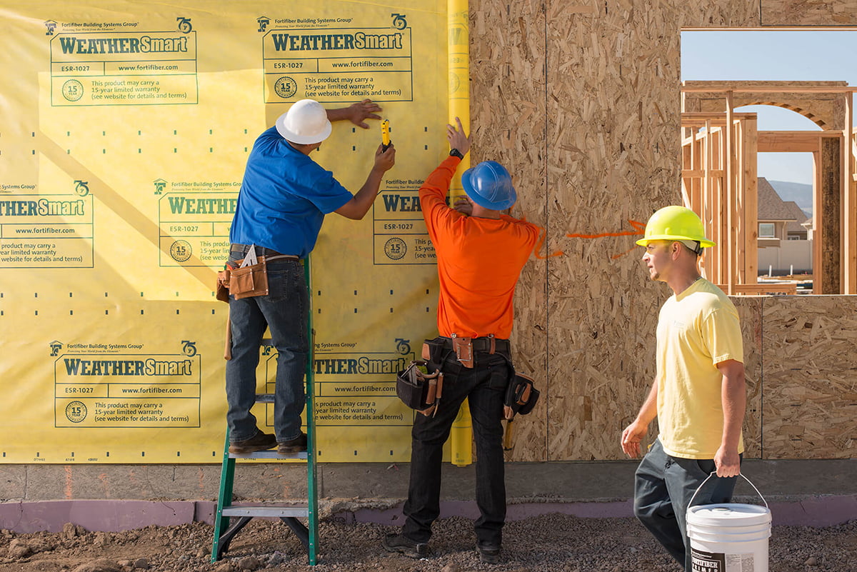 Construction workers applying Fortifiber WeatherSmart House Wrap