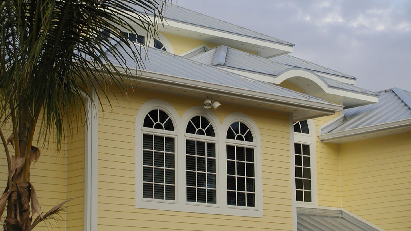 Azek trim with integrated drip edge on yellow home with arched windows