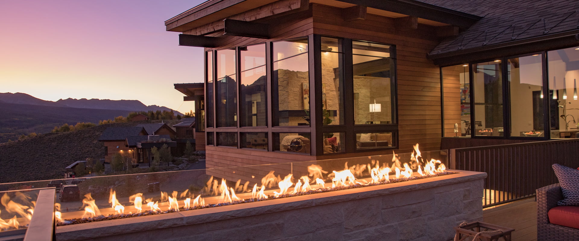 Weather Shield windows on a mountainside home with a large fire pit at sunset