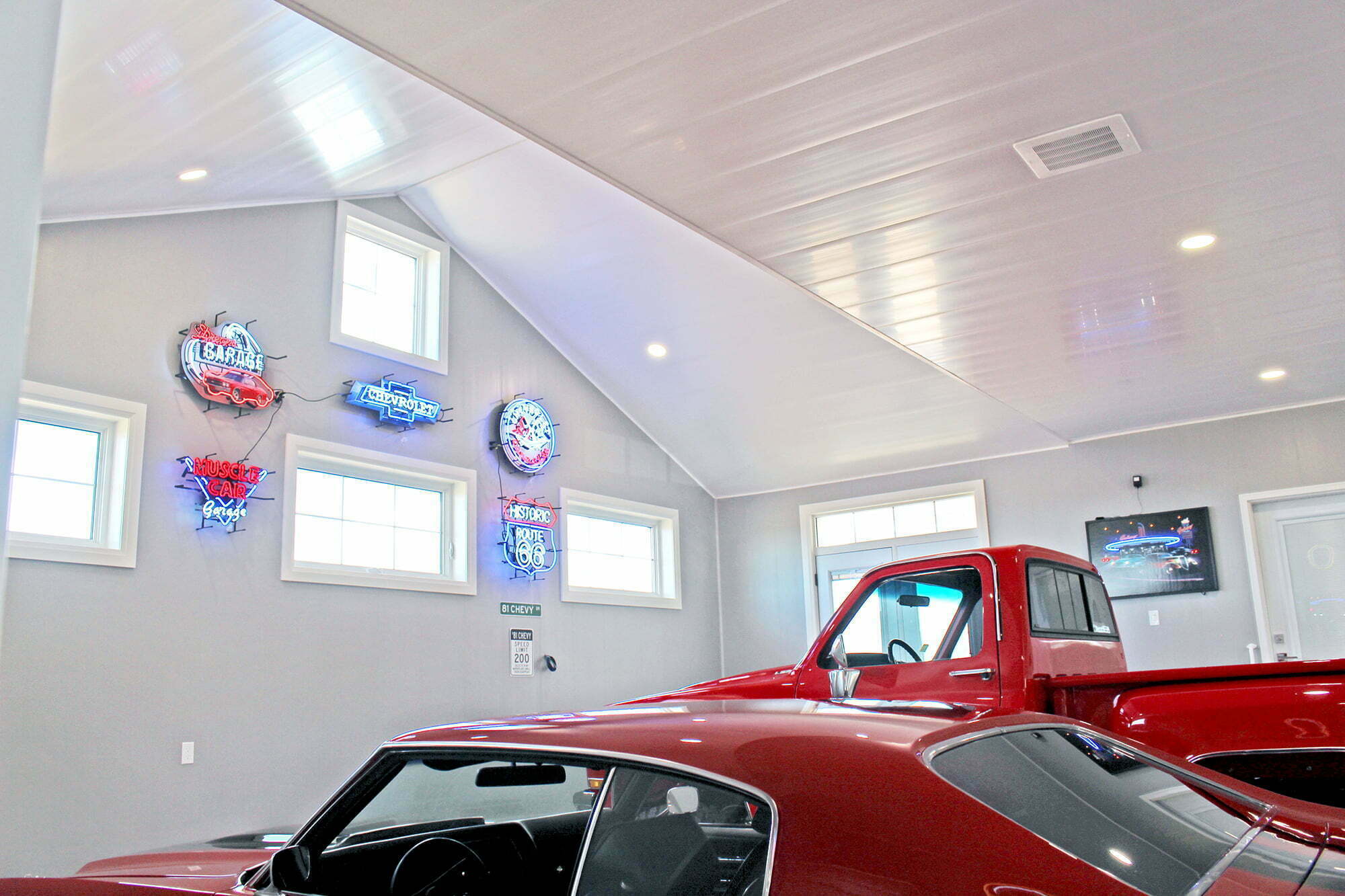 Trusscore inside white garage with neon lights and two red vehicles