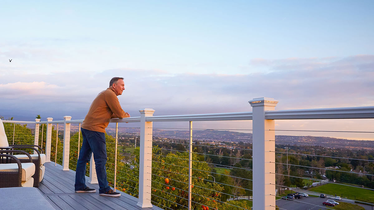 Man standing on a deck at sunset with Feeney CableRail