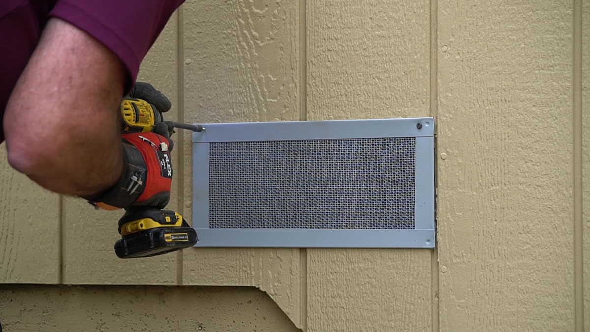 Closeup of person installing a Vulcan Vent foundation vent