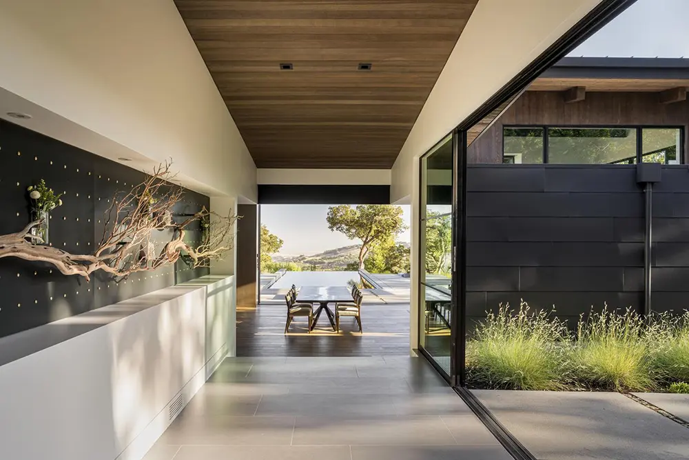 External hallway patio of a Sonoma Mountain home leading to an infinity pool with sliding window wall